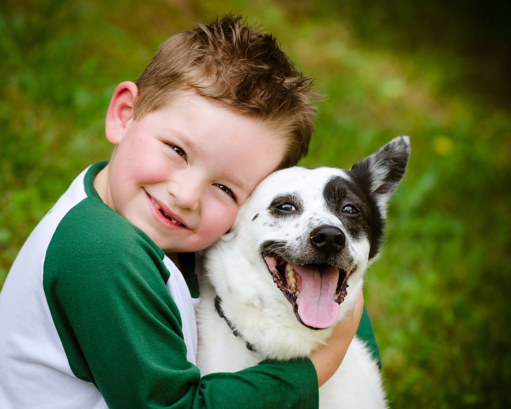 young boy hugging his small dog